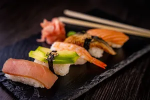 A variety of nigiri sushi including salmon, tuna, shrimp, and avocado on slate plate. jigsaw puzzle