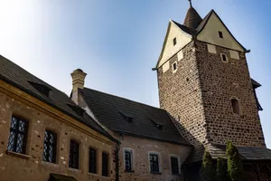 Majestic old stone castle tower and building under a bright blue sky, showcasing medieval architecture. jigsaw puzzle