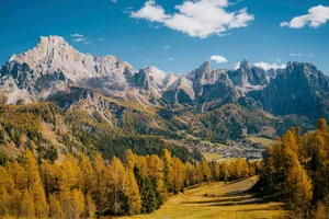 Vibrant autumn trees and majestic mountains under a blue sky. jigsaw puzzle