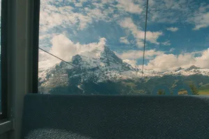 A snow-capped mountain peak viewed from inside a gondola. jigsaw puzzle