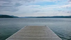 Wooden dock extending into a calm lake under cloudy sky jigsaw puzzle
