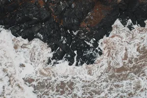 Aerial shot of waves crashing on black rocks at the coast of Karwar, India. jigsaw puzzle