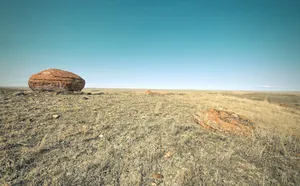 Expansive dry landscape with distinctive red rocks and clear blue sky, showcasing natural beauty. jigsaw puzzle