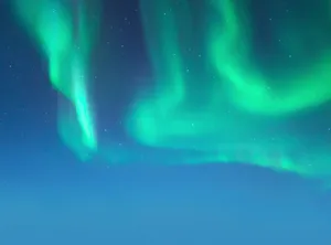 Vibrant green aurora borealis illuminating a clear starry night sky, captured outdoors. jigsaw puzzle