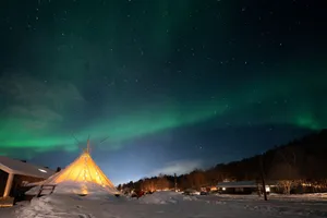 Stunning aurora borealis over a snowy landscape with a lit teepee near Alta, Norway. jigsaw puzzle