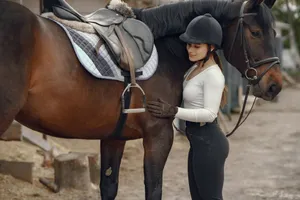Young woman bonding with a saddled horse at an outdoor stable, showcasing a connection. jigsaw puzzle