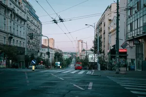 A quiet urban street in the early morning with city buildings and a red bus. jigsaw puzzle