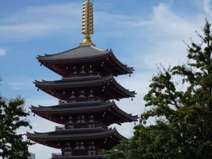 Scenic view of a traditional Japanese pagoda surrounded by trees under a clear blue sky. jigsaw puzzle