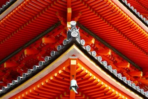 Close-up of vibrant red and orange Japanese temple roof showcasing intricate architectural design. jigsaw puzzle