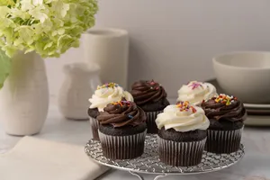 Five chocolate cupcakes topped with frosting and sprinkles on a decorative stand. jigsaw puzzle
