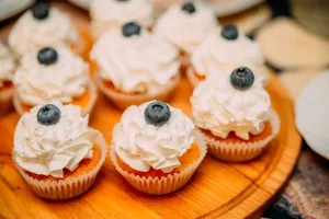 High angle of delicious cakes with creamy topping and berries placed on wooden plate on buffet table jigsaw puzzle
