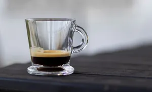 A close-up shot of a rich espresso in a clear glass cup on a dark table. jigsaw puzzle
