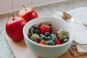 A bowl of fresh berries and apples arranged on a wooden board, perfect for a healthy breakfast. jigsaw puzzle