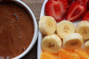 Sliced strawberries, bananas, and oranges with a bowl of rich chocolate sauce. jigsaw puzzle