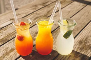 Close-up of three refreshing beverages with citrus, strawberries, and lime on a sunny wooden table. jigsaw puzzle