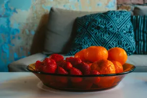 A rustic still life featuring a bowl of fresh oranges and strawberries, exuding a tropical and healthy vibe. jigsaw puzzle