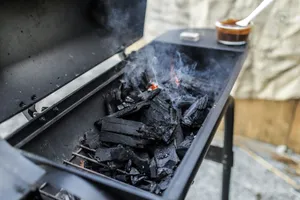 Close-up of a charcoal grill emitting smoke, showcasing burning coals and outdoor cooking setup. jigsaw puzzle
