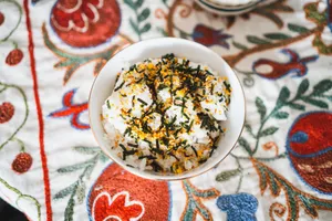 Delicious bowl of seasoned rice topped with seaweed on colorful, embroidered cloth. jigsaw puzzle