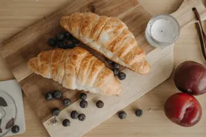 Top view of croissants with blueberries, plums, and candle on a wooden board. jigsaw puzzle