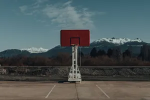 A solitary basketball hoop stands against a stunning mountain landscape under a clear sky. jigsaw puzzle