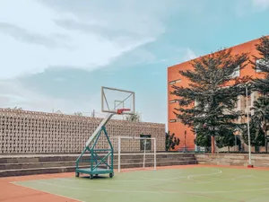 Empty sports ground with basketball hoop and soccer goal on green lawn located near urban building under blue sky jigsaw puzzle