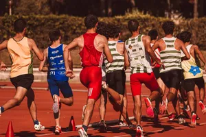 A group of male athletes competing in a track and field event outdoors under a sunny sky. jigsaw puzzle