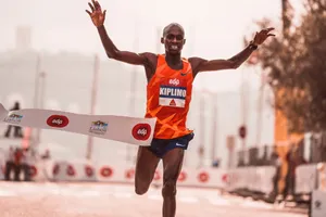 Marathon runner finishes race with arms raised in Lisbon, captured mid-stride at the finish line. jigsaw puzzle