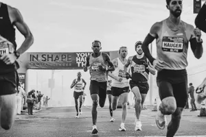Black and white photo of intense marathon runners nearing the finish line under a large banner. jigsaw puzzle