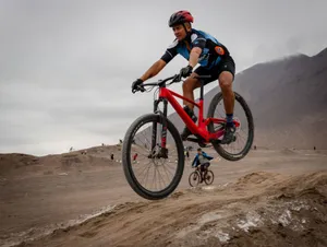 Mountain biker performing a jump on a rugged off-road track during a race. jigsaw puzzle