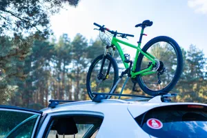 A green mountain bike mounted on a car roof, set against a forest backdrop. jigsaw puzzle