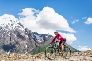 A cyclist rides through a mountainous trail on a sunny summer day, showcasing adventure and freedom. jigsaw puzzle