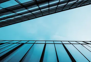 Striking low-angle shot of glass buildings against a clear blue sky, showcasing modern architectural design. jigsaw puzzle
