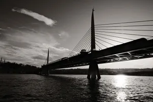 A striking black and white image of a cable-stayed bridge at sunset, with reflective waters below. jigsaw puzzle