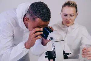 Two scientists in a laboratory examining samples through a microscope, focusing on scientific research. jigsaw puzzle