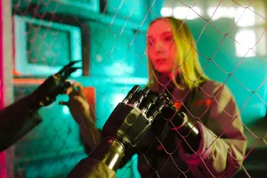 A woman interacts with a robotic hand through a fence under neon lights. jigsaw puzzle