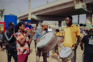 Street musicians playing trumpet and drums in a vibrant outdoor setting under a bridge. jigsaw puzzle