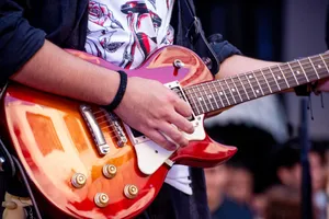 Vibrant close-up of a guitarist performing with a red electric guitar at an outdoor event. jigsaw puzzle