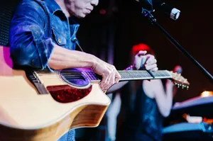 A close-up of a guitarist performing live on stage, focusing on the acoustic guitar. jigsaw puzzle