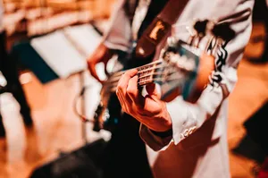 Close-up of a musician playing a bass guitar with a blurred background, warm tones. jigsaw puzzle