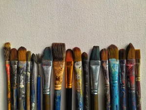 A collection of various paintbrushes aligned against a textured canvas surface. jigsaw puzzle