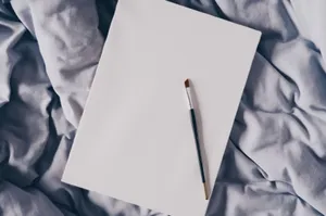 A minimalist flat lay of a paintbrush on a blank canvas resting on soft fabric, ideal for artistic projects. jigsaw puzzle