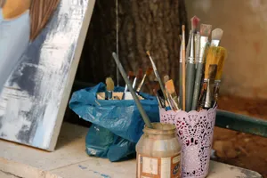 A collection of paint brushes beside an unfinished canvas outdoors in Damascus, Syria. jigsaw puzzle