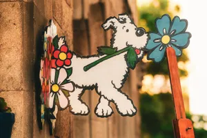 Colorful cartoon dog sign featuring vibrant flowers outdoors in a warm setting. jigsaw puzzle