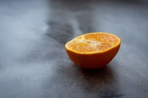 Half of ripe juicy orange placed on black table in kitchen in daylight jigsaw puzzle