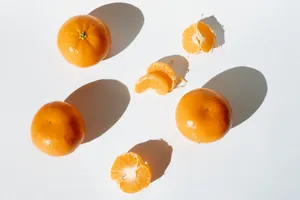 Bright and fresh mandarins with slices casting dramatic shadows on a white surface. jigsaw puzzle