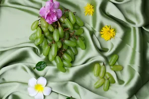 A vibrant arrangement of green grapes and flowers on satin fabric, creating a fresh and elegant composition. jigsaw puzzle